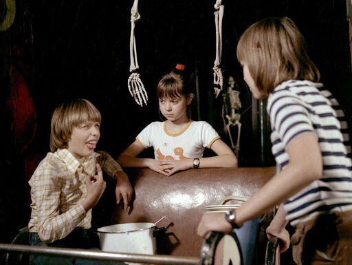 Drei Kinder im Gespräch miteinander, Skelettarme hängen über ihnen. »Spuk unterm Riesenrad«: die Ausreißer Umbo (Dima Gratschow), Keks (Katrin Raukopf) und Tammi (Henning Lehmbäcker) (v.l.n.r.).